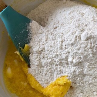 Una ciotola con farina e liquido giallo e una spatola dentro.