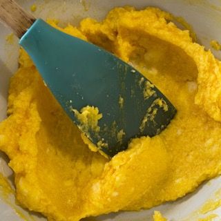Una spatola blu è in una ciotola di purè di patate giallo