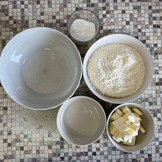 Un tavolo con ciotole di farina e burro sopra