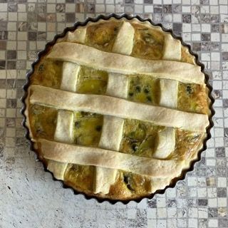 Una torta con la crosta a reticolo è appoggiata su un tavolo a scacchi.