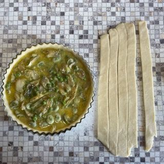 Una torta con piselli e pollo accanto a un pezzo di pasta