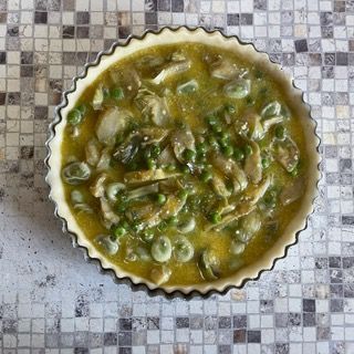 Una torta ripiena di funghi e piselli su un tavolo a scacchi
