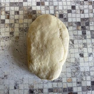 Un pezzo di pasta è appoggiato su un piano piastrellato.