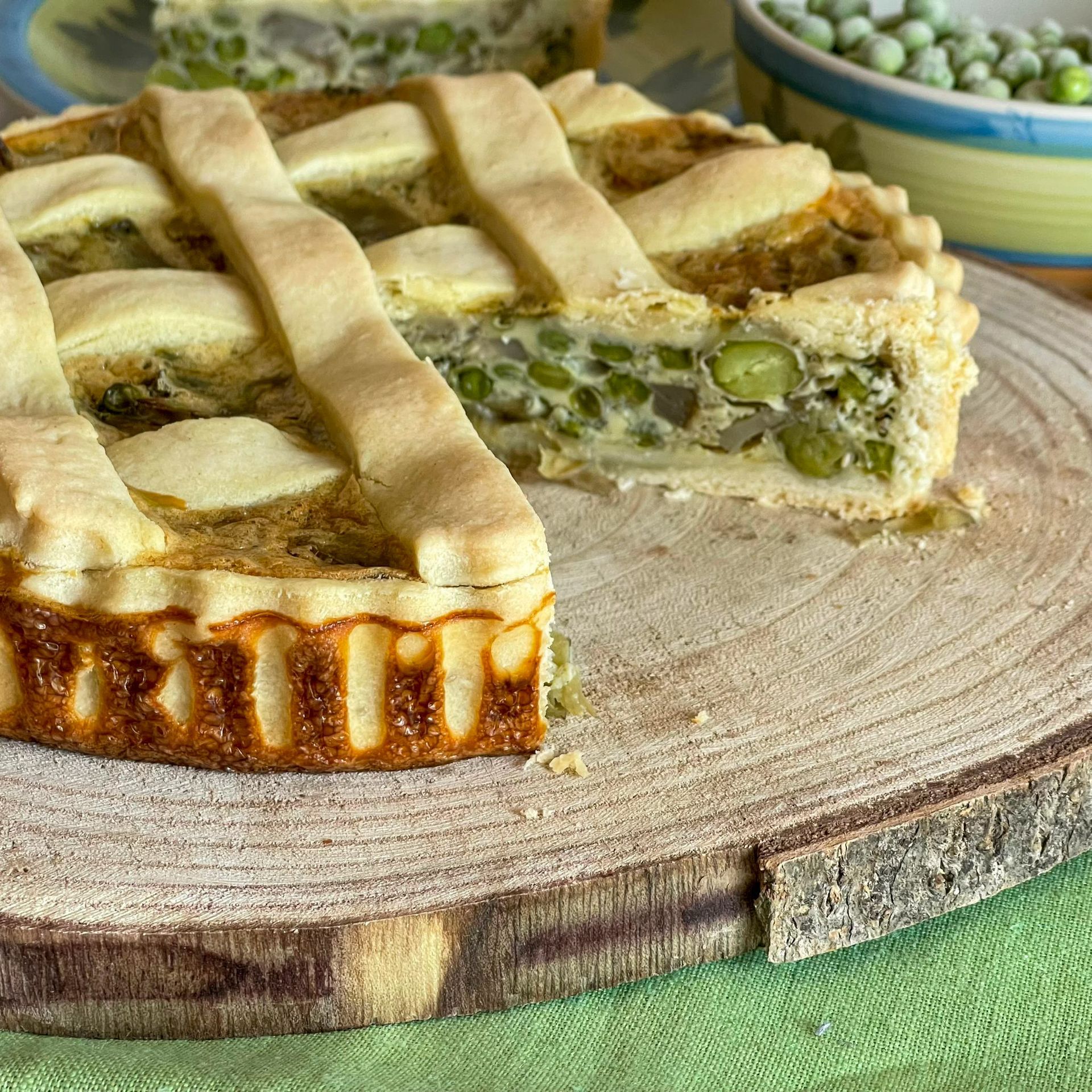 Una torta con una fetta tagliata è appoggiata su un tagliere di legno.