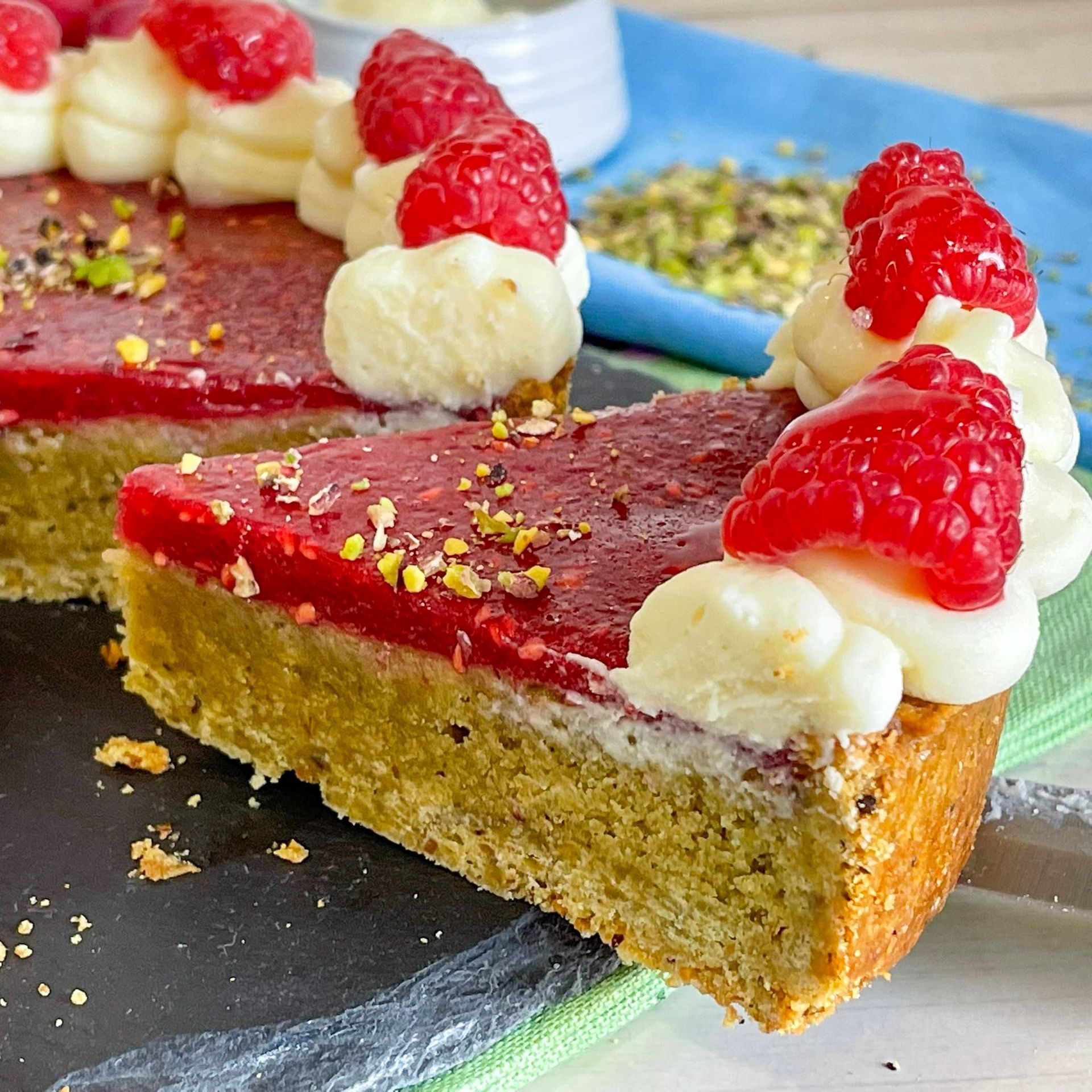 Una fetta di torta con lamponi e panna montata sopra.