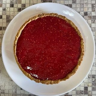 Un piatto bianco sormontato da una torta ai lamponi
