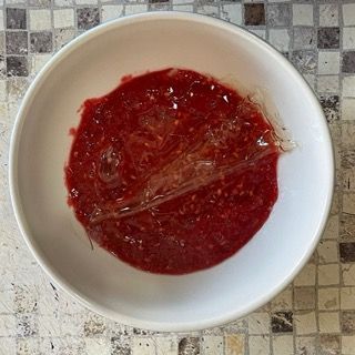 Una ciotola bianca piena di liquido rosso su un tavolo