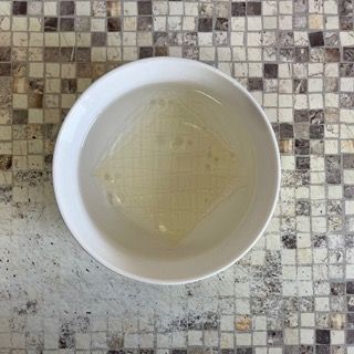 Una ciotola di liquido è appoggiata su un tavolo a scacchi