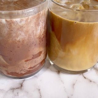Due bicchieri di cioccolata e caffè sono appoggiati su un tavolo.