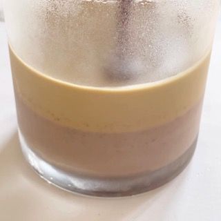 Un primo piano di un bicchiere di caffè con un cucchiaino dentro.