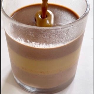 Un primo piano di un bicchiere di budino al cioccolato con un cucchiaio dentro