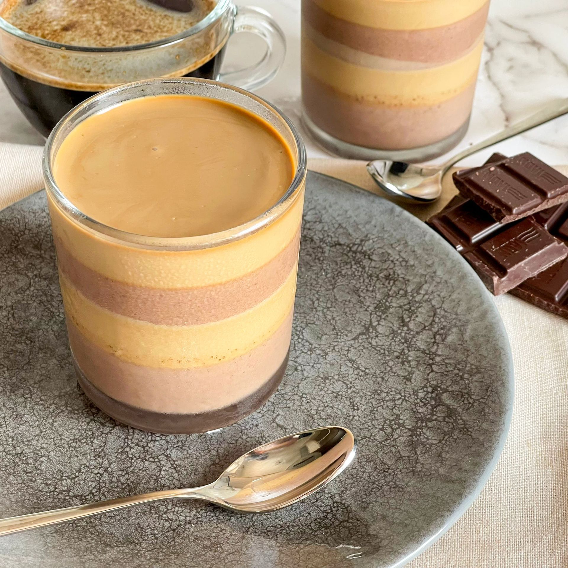 Un primo piano di una tazza di caffè su un piatto con un cucchiaio.
