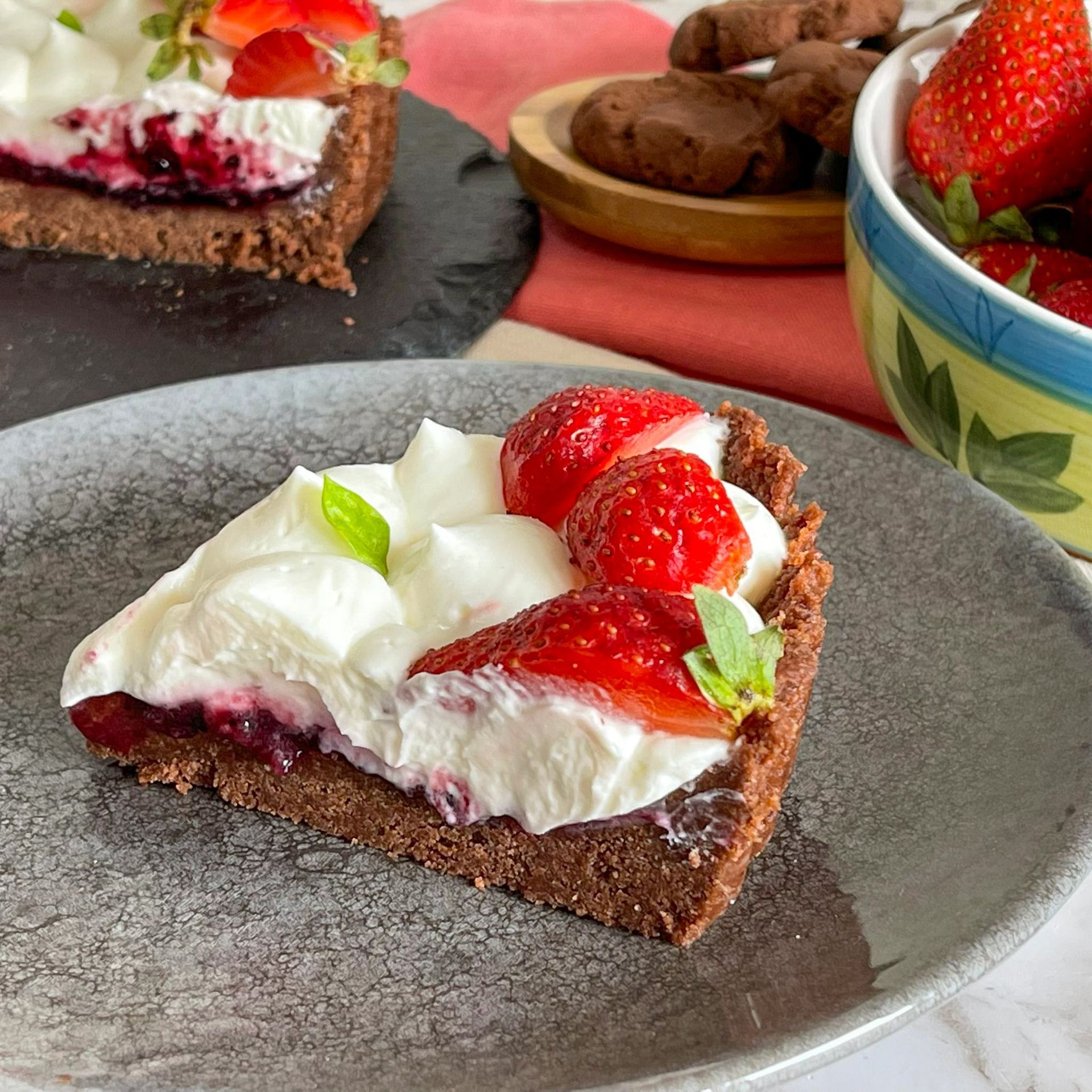 Una fetta di torta con fragole e panna montata su un piatto.