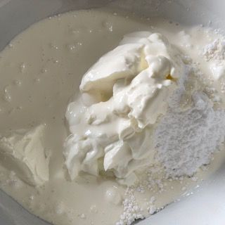 La panna montata viene aggiunta a una ciotola di zucchero a velo.