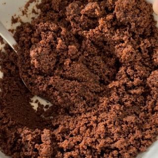Una ciotola di polvere marrone con un cucchiaio dentro