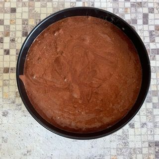 Una ciotola di salsa al cioccolato è appoggiata su un tavolo a scacchi.