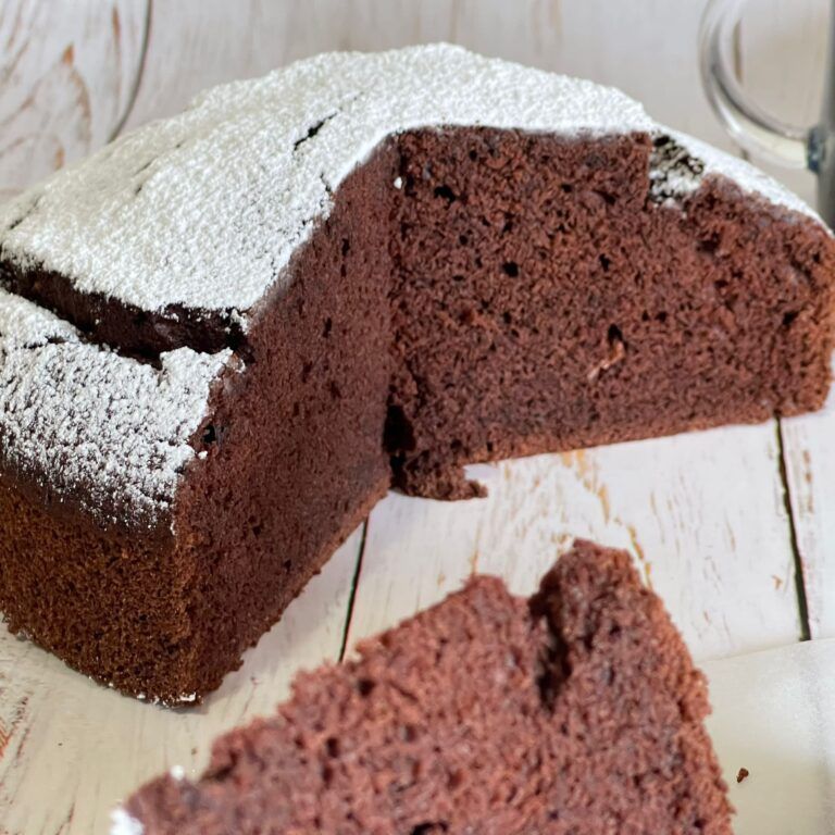Una torta al cioccolato con zucchero a velo sopra e una fetta tagliata fuori