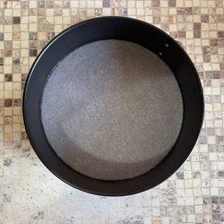 Una tortiera è appoggiata su un piano piastrellato.