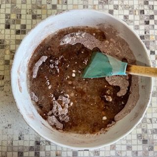 Una ciotola di liquido marrone con una spatola dentro