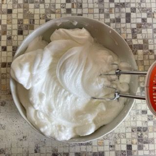 Una ciotola di panna montata accanto a un mixer