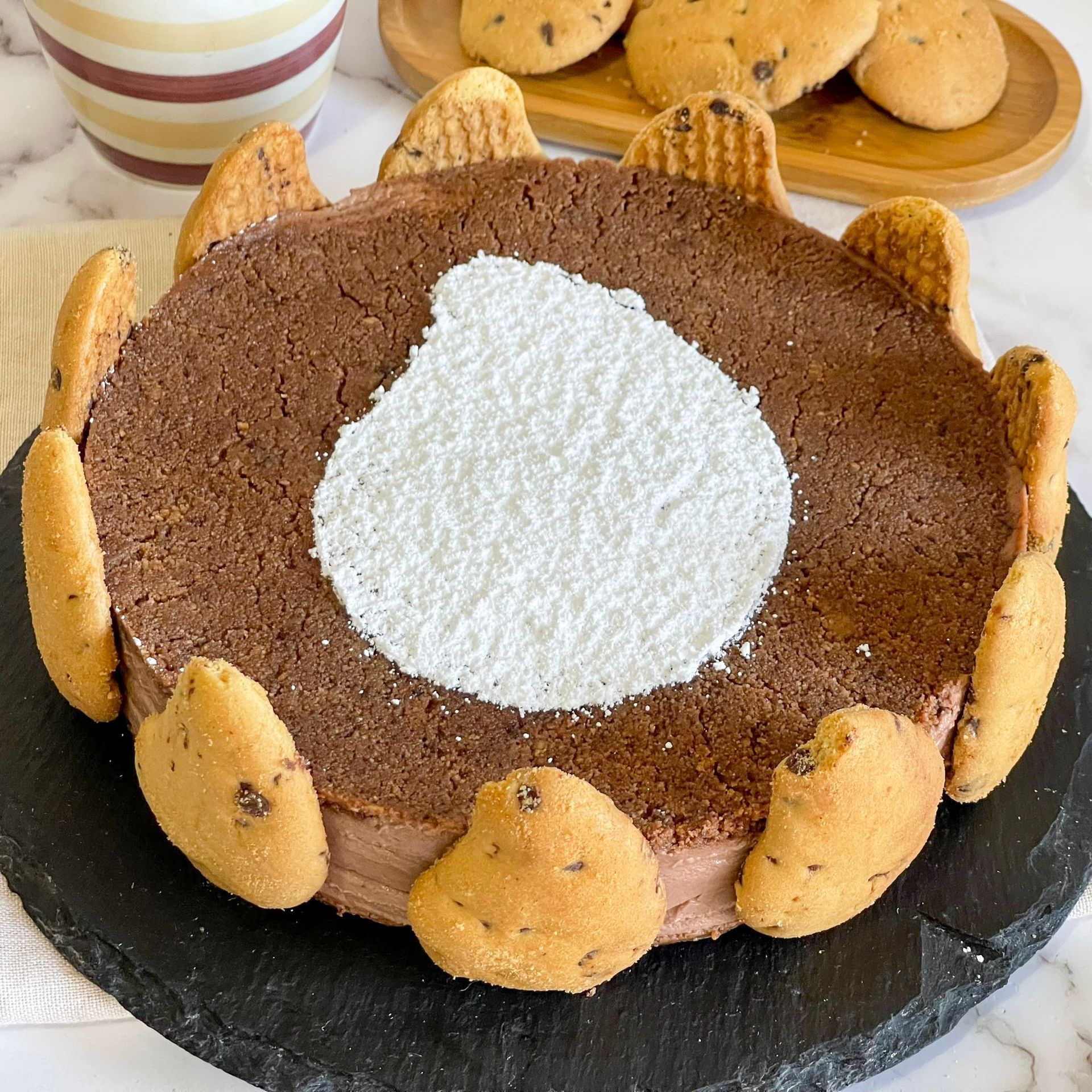 Una torta al cioccolato con dei biscotti sopra è su un piatto nero.