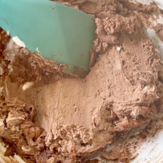 Primo piano di una ciotola di glassa al cioccolato con una spatola.