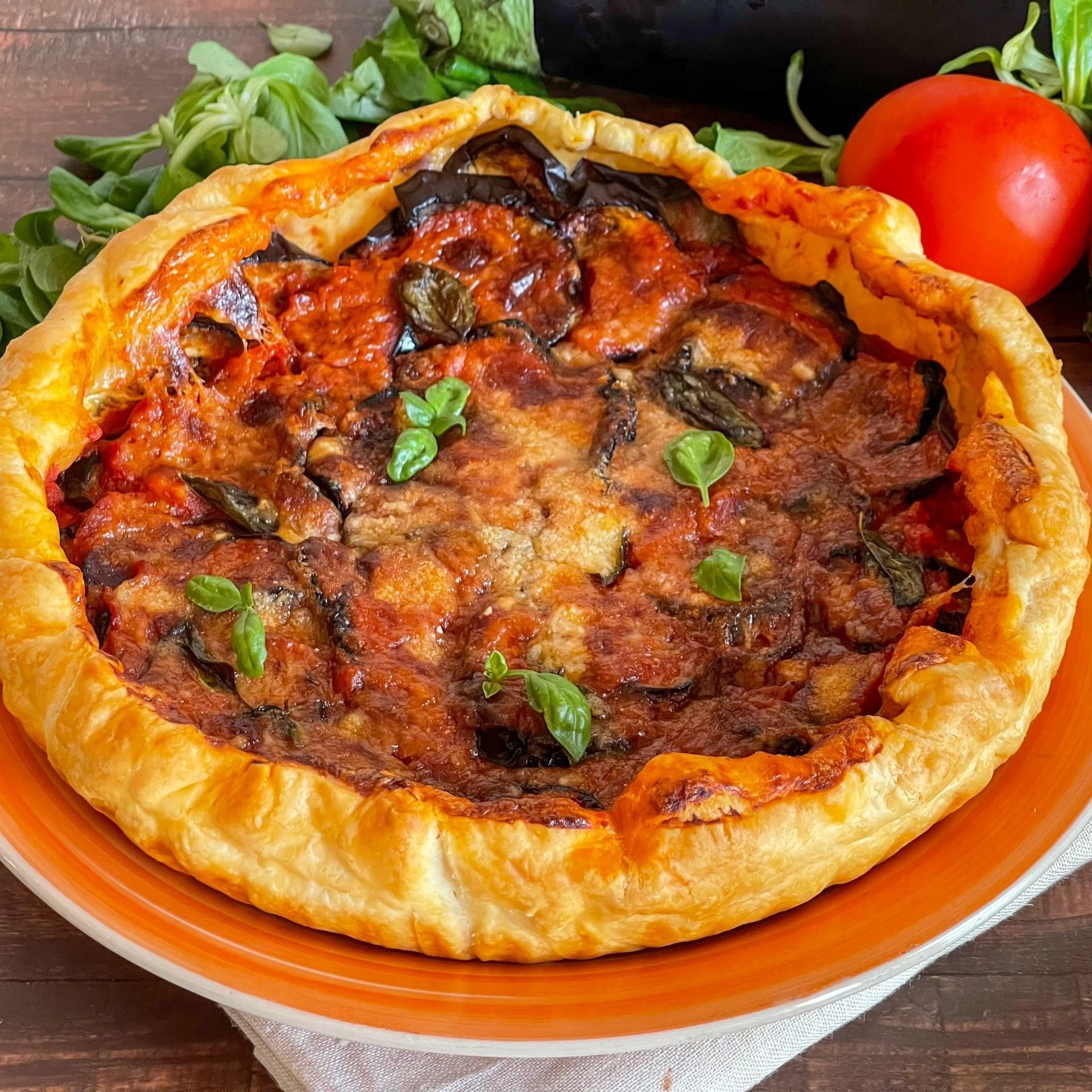 Una pizza con salsa di pomodoro e basilico su un piatto arancione.