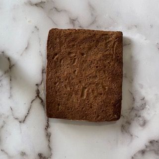 Un biscotto marrone è appoggiato su una superficie di marmo bianco.