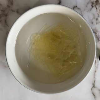 Una ciotola d'acqua con dentro dei noodles su un tavolo.