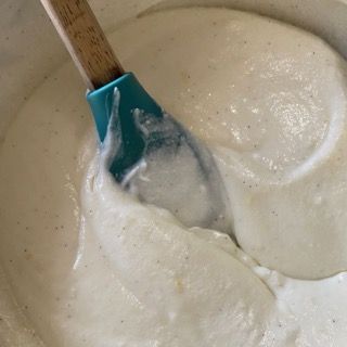 Una spatola blu è in una ciotola di besciamella.