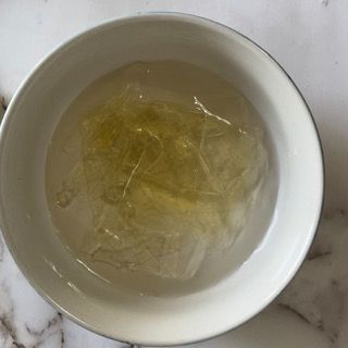 Una ciotola bianca piena di liquido è appoggiata su un tavolo.
