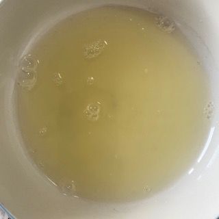 Primo piano di una ciotola piena di liquido con delle bollicine al suo interno.