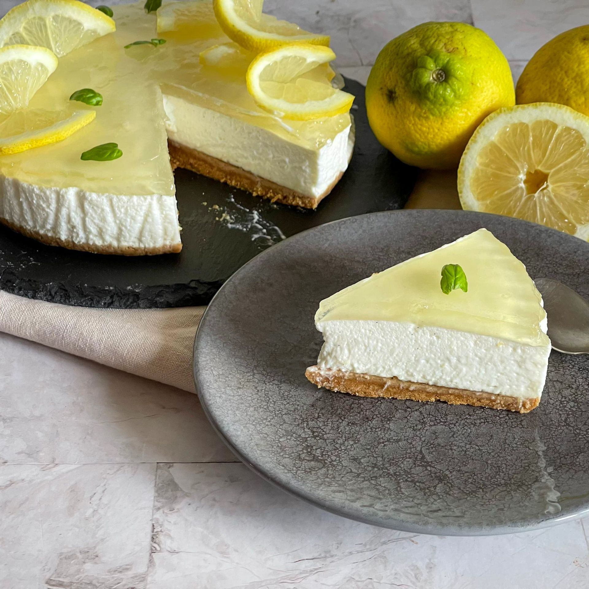Una fetta di cheesecake al limone su un piatto accanto a una torta