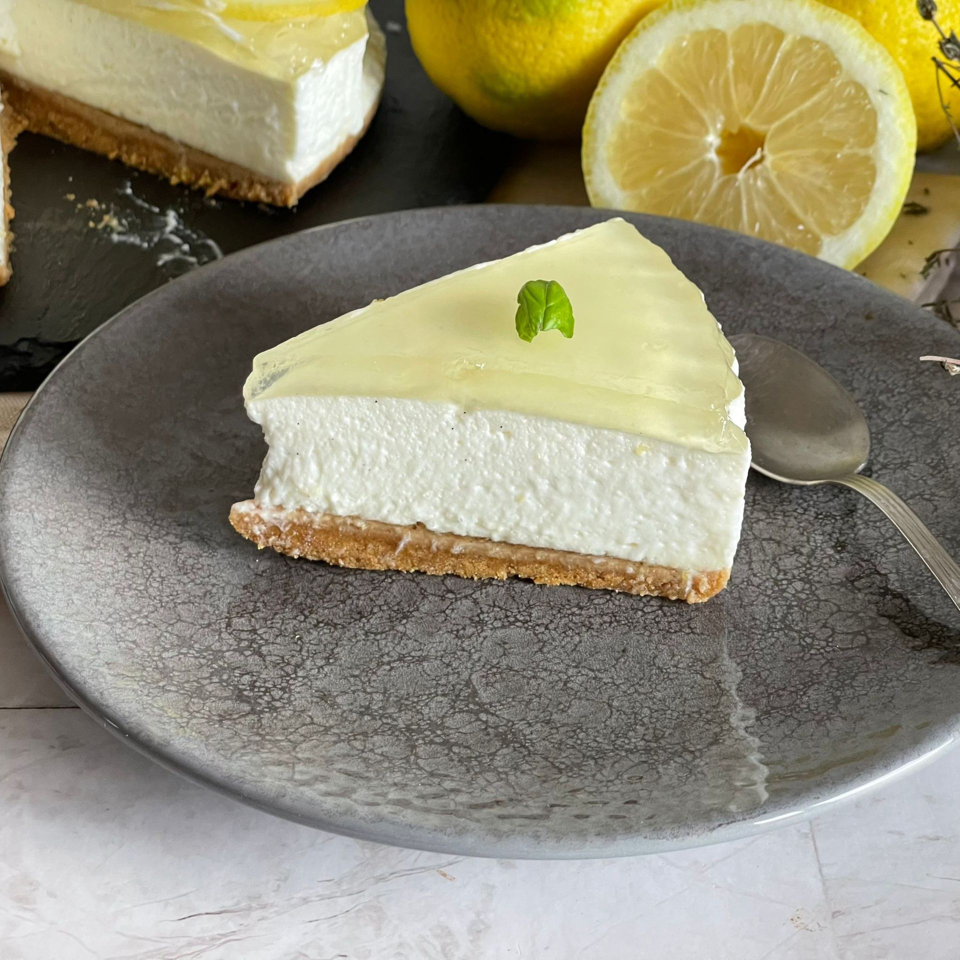 Una fetta di cheesecake al limone è su un piatto con un cucchiaio.