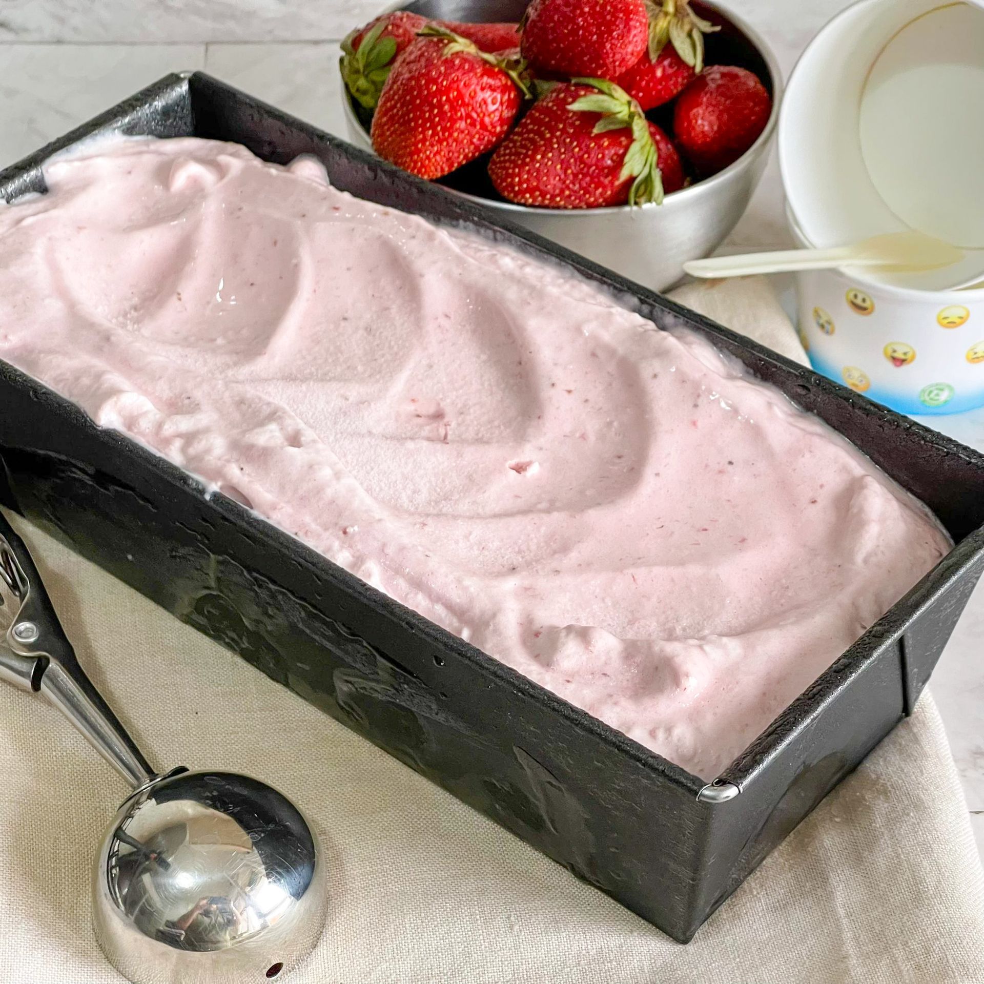 Una pagnotta di gelato alla fragola accanto a una ciotola di fragole
