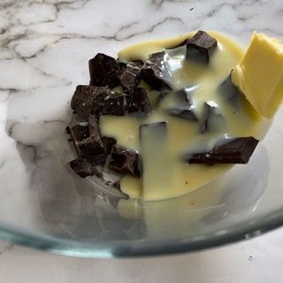 Una ciotola di vetro piena di cioccolato e un pezzo di burro