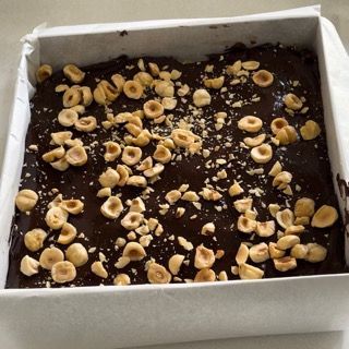 Una torta al cioccolato con noci sopra in una scatola