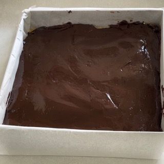 Una scatola bianca piena di glassa al cioccolato su un tavolo.
