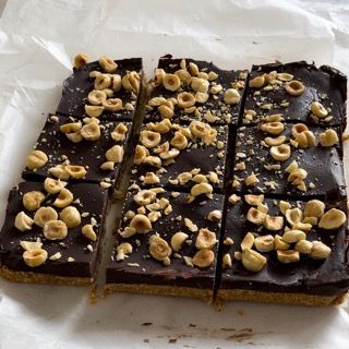 Una barretta di cioccolato con sopra delle noci viene tagliata a quadratini