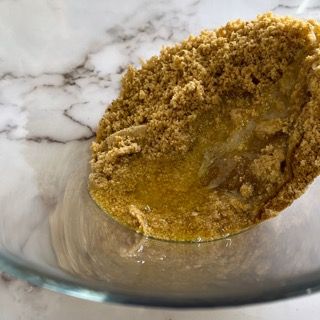 Una ciotola di vetro piena di polvere marrone e liquido su un tavolo.