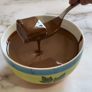 Una persona sta immergendo un pezzo di cioccolato in una ciotola di salsa al cioccolato