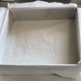 Una scatola quadrata ricoperta di carta oleata è appoggiata su un bancone.