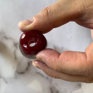 Una persona tiene in mano una ciliegia rossa.