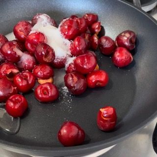Una padella piena di ciliegie e zucchero su un fornello