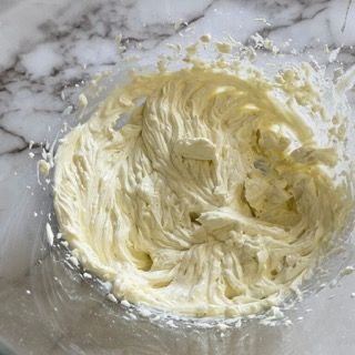 Una ciotola di panna montata è su una superficie di marmo.