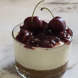 Un dessert in un bicchiere con ciliegie sopra