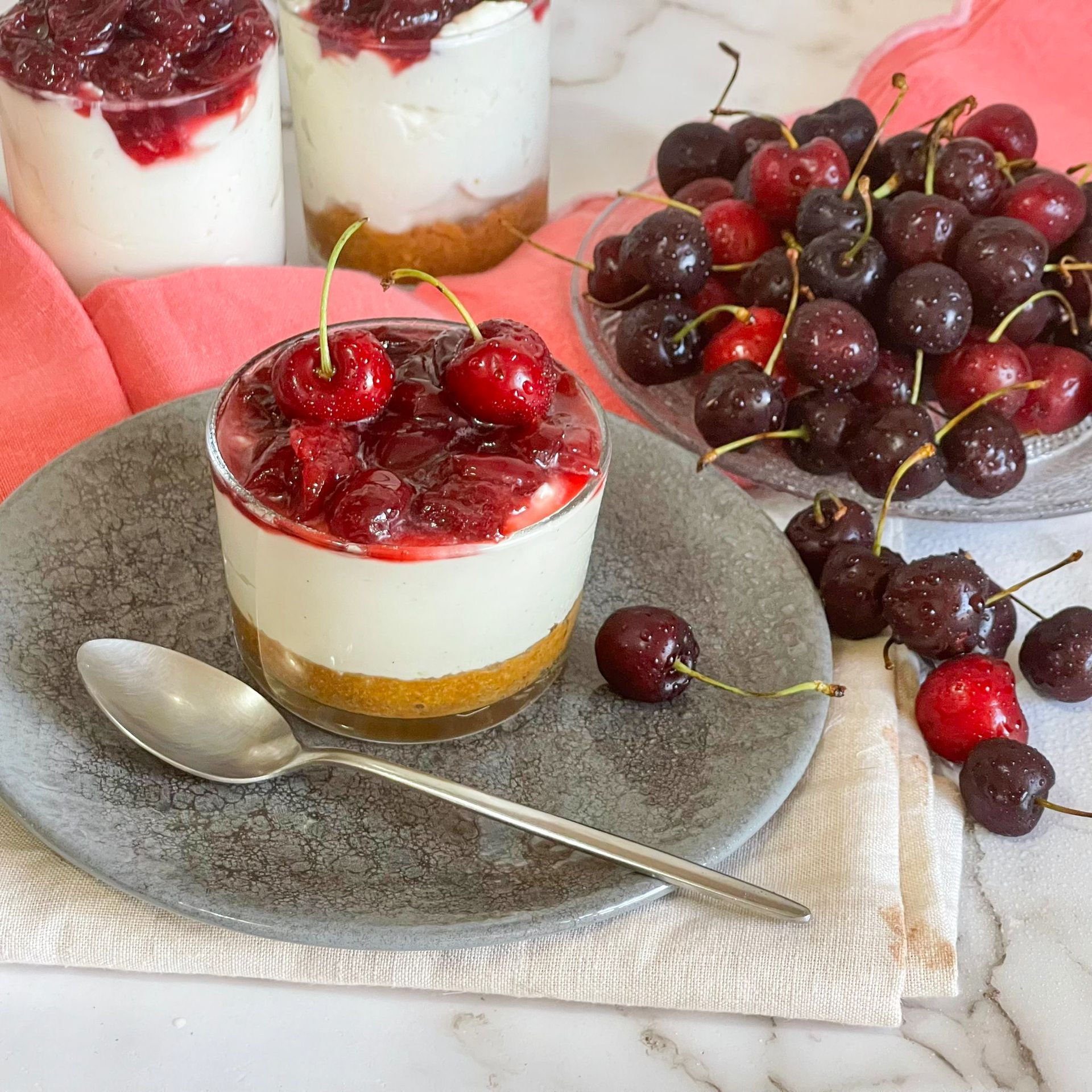 Un dessert con ciliegie sopra è su un piatto con un cucchiaio