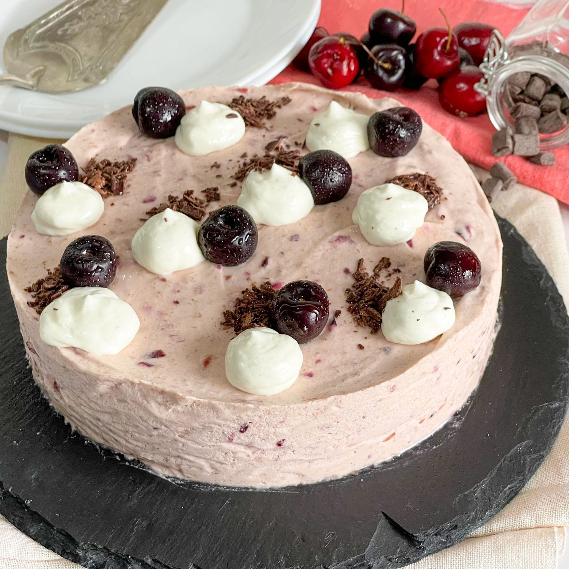 Una torta con ciliegie e panna montata sopra