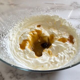Una ciotola di vetro piena di panna montata e salsa al caramello.