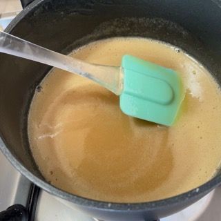 Una spatola verde è in una pentola piena di liquido.